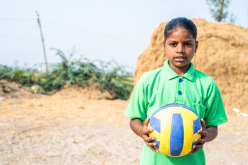 sweat Village teenage girl with football standing near paddy field after playing showing with copy...