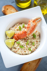 Risotto with crab meat and boiled crab claw in a white plate, high angle view, vertical shot, closeup
