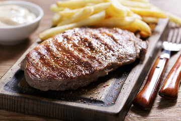 grilled meat with french fries on a wooden board