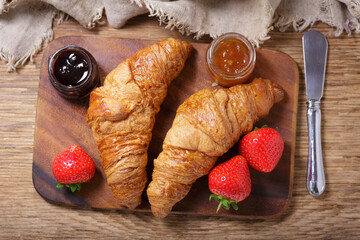 fresh croissants and strawberry on wooden board