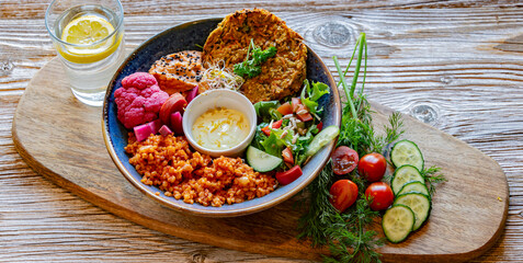 Vegan plate with millet cutlet, bulgur groats and vegetables