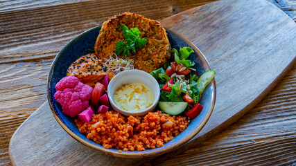Vegan plate with millet cutlet, bulgur groats and vegetables