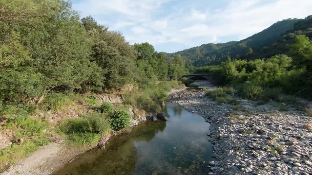 Rivi&egrave;re qui coule au milieu des bois et des champs au printemps jusqu'&agrave; un pont dans les C&eacute;vennes dans le Sud de la France.
