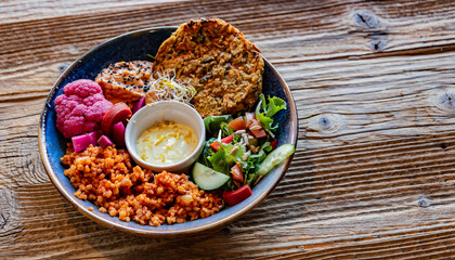 Vegan plate with millet cutlet, bulgur groats and vegetables