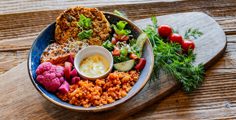 Vegan plate with millet cutlet, bulgur groats and vegetables