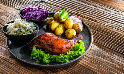 Fototapeta na wymiar Baked chicken leg with potatoes and vegetable salads