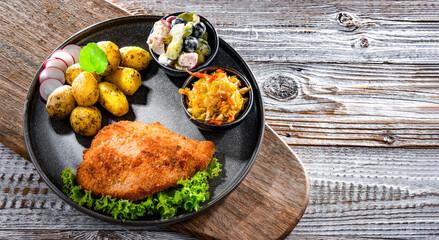 Pork cutlet coated with breadcrumbs with potatoes and salads