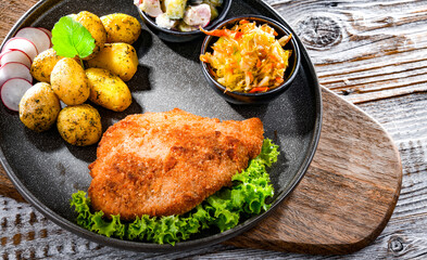 Pork cutlet coated with breadcrumbs with potatoes and salads