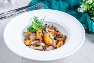 Fried potatoes with mushrooms on a white bowl