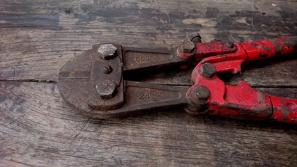 A rusty bolt cutter against the background of old wooden boards painted in light blue