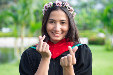 Successful college student with laurel crown in commencement day showing study loving heart hand...