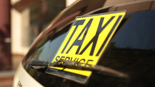 Yellow taxi service sticker on the rear window of the car on the parking in the Public space
