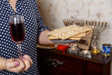 A Jewish woman with a glass of wine and matzah in her hands before the Seder on Pesach.