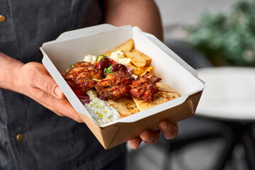 Greek souvlaki,salad and gyros take away. menu, serving in recyclable paper container in the hands of the chef.