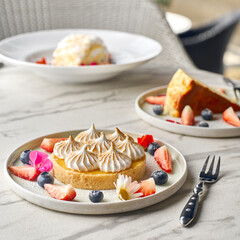 Lemon pie on the table with citrus fruits. Traditional french sweet pastry tart. Delicious, appetizing, homemade dessert with lemon curd cream.