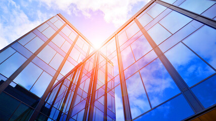 Glass buildings with cloudy blue sky background.  Perspective wide angle view to steel light blue background of glass.  Commercial modern city of future. Business concept of successful  architecture.