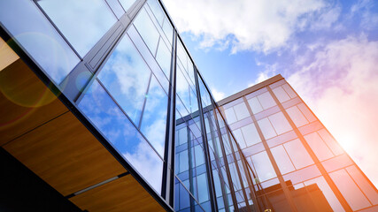 Obraz premium Glass buildings with cloudy blue sky background. Perspective wide angle view to steel light blue background of glass. Commercial modern city of future. Business concept of successful architecture.