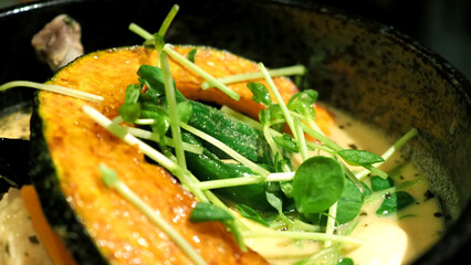 Close-up images of yellow color soup curry with chicken, pork and vegetable in bowl which famous traditional food menu and only found in Hokkaido Sapporo district of Japan 