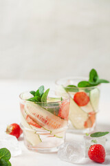Summer refreshing iced drinks with cucumber,  strawberry and mint on white background