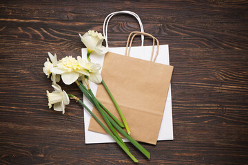 Yellow daffodil flowers and paper bag on wooden background. Top view.