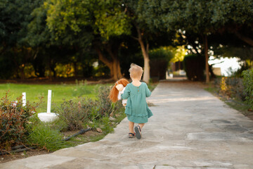 A child girl in a casual dress with a doll walks around the hotel alone, child safety, kid hugging waldorf doll