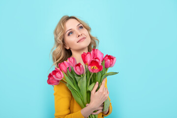 dreamy happy young woman with spring tulip flowers on blue background