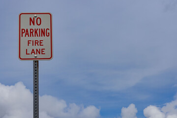 No Parking Fire Lane White and Red Sign in front of Clouds