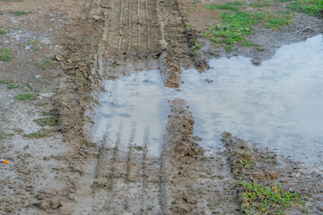 Big car wheel trace on road, puddle and mud