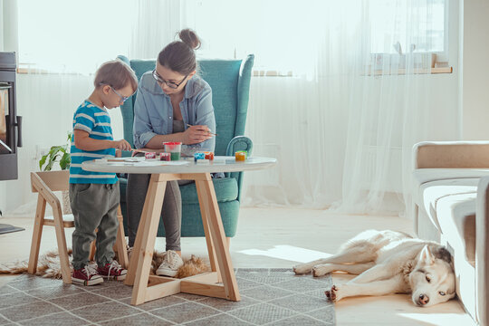 Mom and child paint together at home with dog