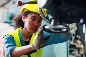 Woman worker wearing safety goggles control lathe machine to drill components. Metal lathe...