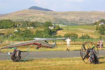 Paramotor and powered hangliders being prepared in a field	
