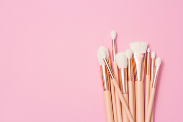 Cosmetic white brushes, everyday makeup tools on pink background, closeup. Flatlay.