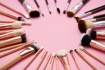 Cosmetic brushes, everyday makeup tools on pink background, closeup. Flatlay.