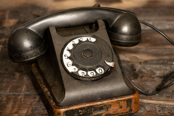 Old black retro phone on a wooden table, rotary phone