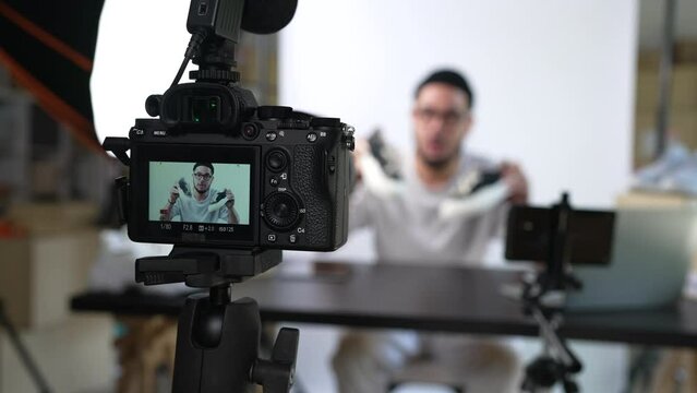Young attractive Asian man blogger or vlogger looking at camera reviewing product and merchandise. Business online influencer on social media concept.