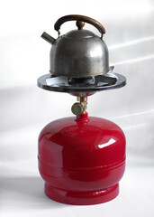 Kettle on the compact metal gas cylinder and burner for camping stove.