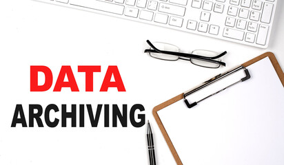 DATA ARCHIVING text written on white background with keyboard, paper sheet and pen