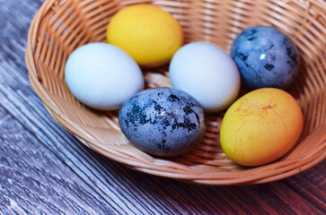 Obraz na płótnie Canvas Multi-colored Easter eggs in a basket on a dark background