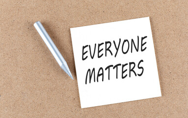 EVERYONE MATTERS text on sticky note on cork board with pencil ,