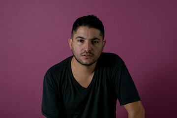 Obraz premium serious looking at camera surprised , camera , young brunet man, 20s, wears blue shirt looking at camera smiling isolated on light pink background studio portrait. People emotions lifestyle concept
