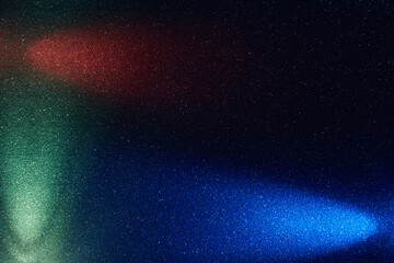 On a black background in fine grain, rays of blue red and turquoise light