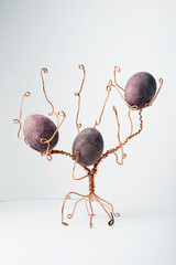 copper wire tree decorated with painted Easter eggs and leaves