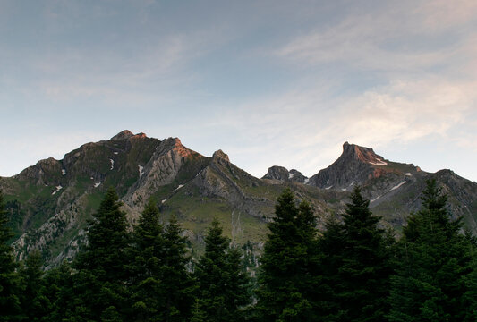 A mountain side of a Greek mountain late in the evening with thin clouds turning into orange before the sunset