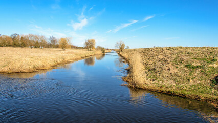 Landscape with a footbridge over a canal on a spring sunny day.
