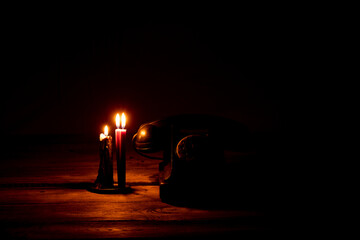Old black retro telephone on a wooden table in the dark near the flame of candles, telephone , phone ringing in the dark