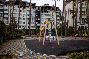 Fototapeta na wymiar Irpin, Kyev region Ukraine - 09.04.2022: Playground in the courtyard of the house after the Russian occupation. Against the background of the house in which rockets hit. Houses after the fire.