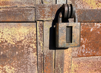 A large metal barn lock on a rusty iron door.