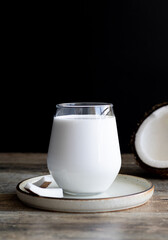 Glass of coconut milk and coconuts on wooden background with copy space. lactose free milk. Healthy food concept, gluten free diet.