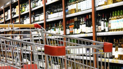 Close-up of a shopping trolley against many shelves of wine in a liquor department