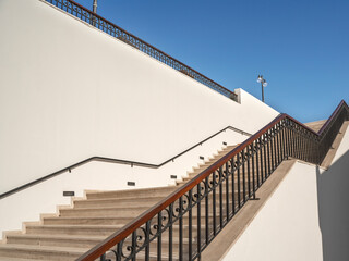 Wide staircase uphill with stone steps along a light wall. Career growth concept.